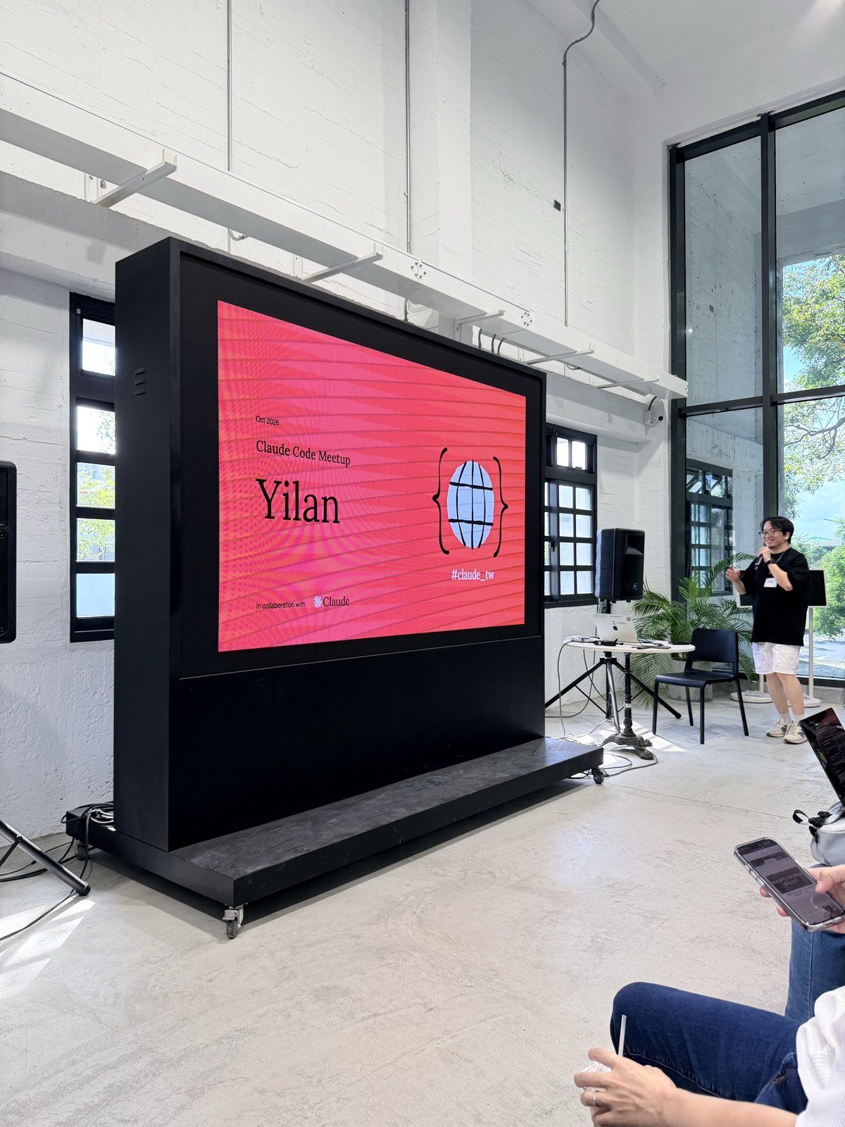 會場大螢幕顯示Claude Code Meetup Yilan主視覺，高見龍在螢幕旁開場